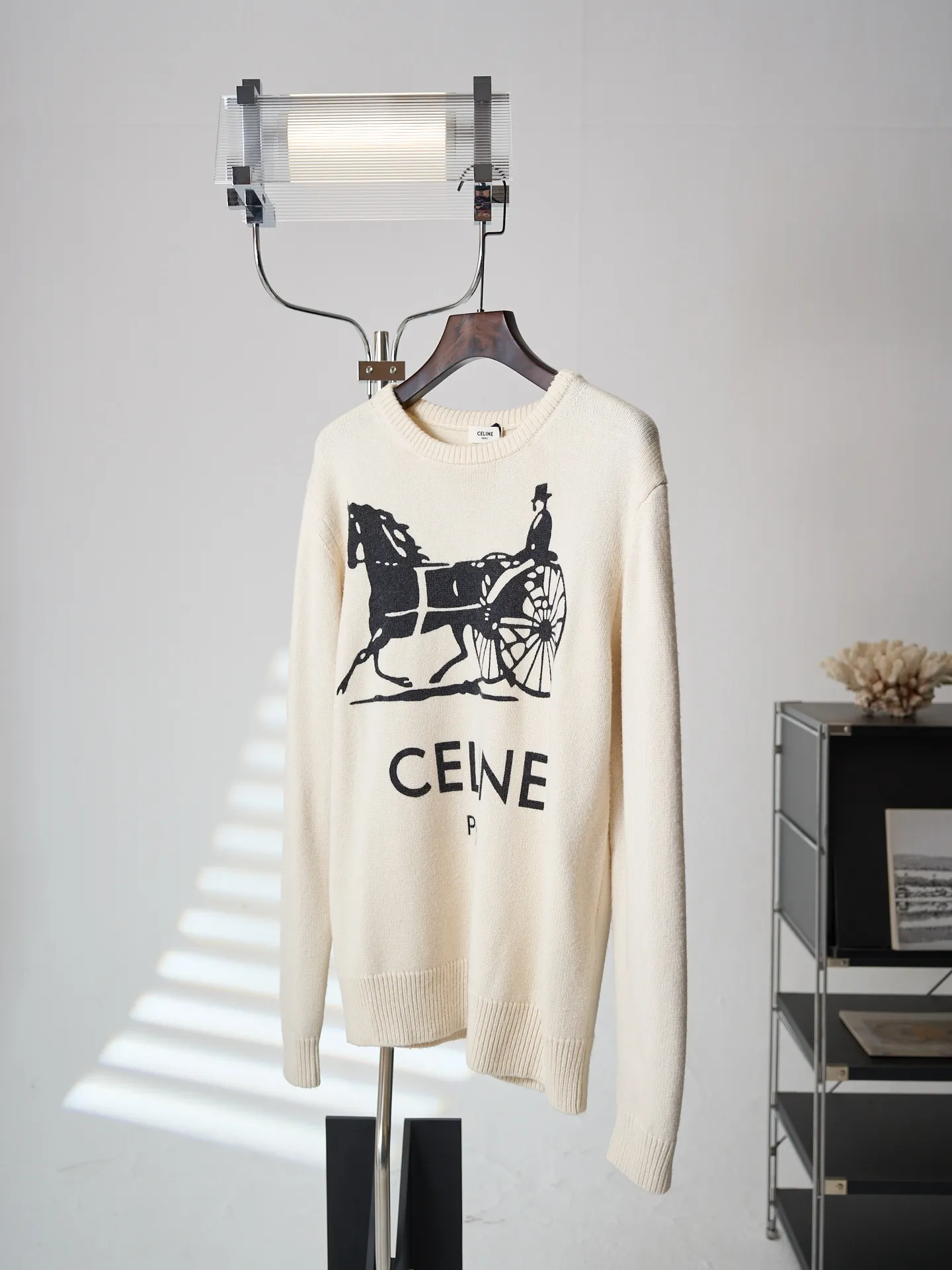 [Real object hanging] CELINE/Celine carriage print round neck knitted sweater [In Stock] S M L XL Fabric selection: Made of 62% wool + 23% nylon + 15% anti-pilling acrylic blended yarn, precision woven on an imported 7-needle knitting machine. The 7-needle medium-thick knitted structure makes the fabric fluffy and thick, with excellent temperature-locking ability; wool gives the fabric a soft, waxy and skin-friendly texture, while nylon strengthens the toughness and prevents it from loosening and deforming. It is paired with anti-pilling acrylic to give it both comfort and durability, and a solid texture. Printing process: The Classic carriage pattern and letters on the chest adopt a reactive printing process. The dye penetrates into the knitted fiber and is not offset printed on the surface. The pattern lines are clear and neat, and the touch is natural without a hard glue layer. It is not easy to crack or peel after repeated wear and washing, and the original soft texture of the knitted fabric is completely retained. Details: The round neck, cuffs and hem are made of high-density wide rib weaving, which has long-lasting elasticity and will not loosen easily after long-term wear; the back shoulders are made of hollow keyhole technology, and the entire line is evenly routed.
